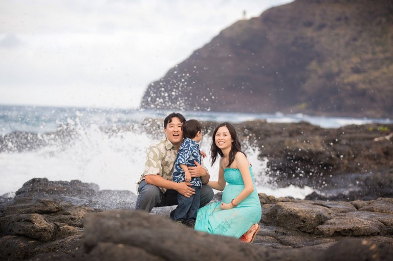 wave spluttering behind a family photo at makapuu beach