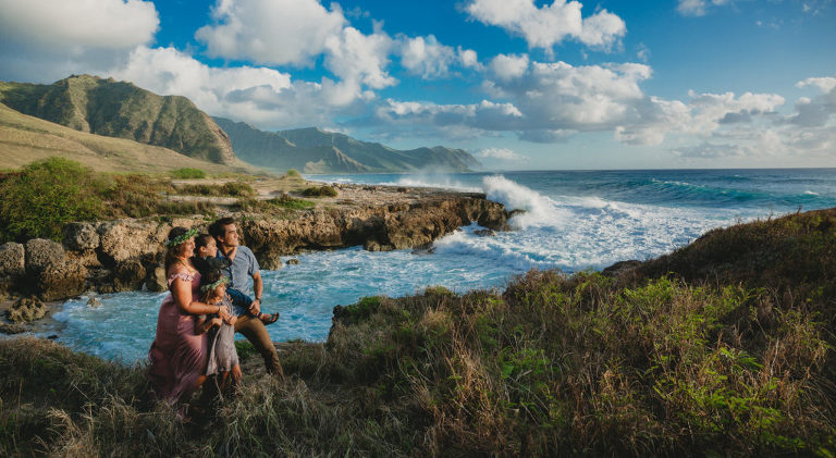 photo of family standing on cliff near ocean waves