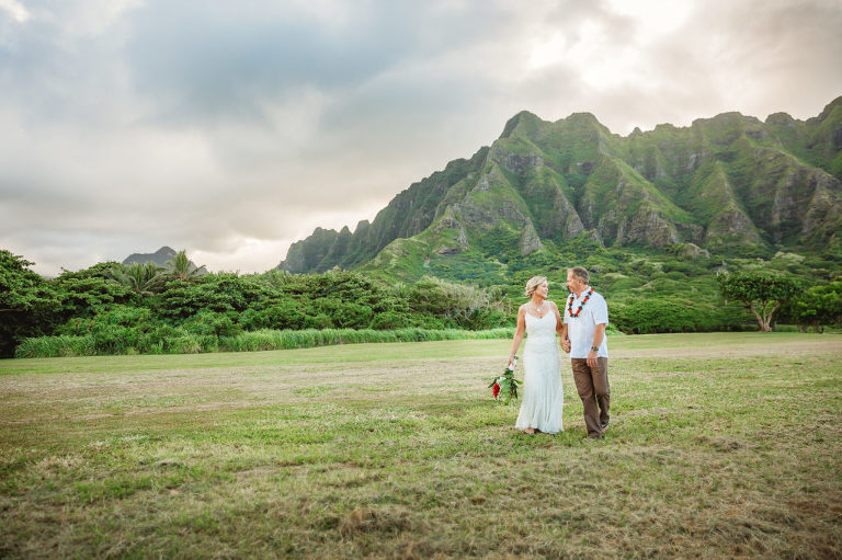 Newlyweds walking across field on north shore oahu