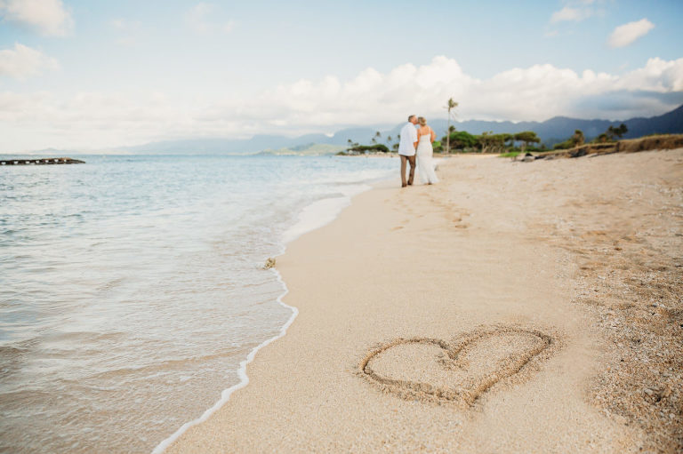 Wedding couple walking on Kualoa Beach in the distance