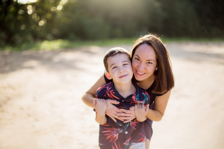 mom hugging son photographed on beach