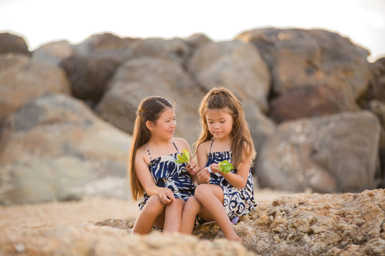 sisters sitting on the shore near Ko Olina lagoons for family photography shoot