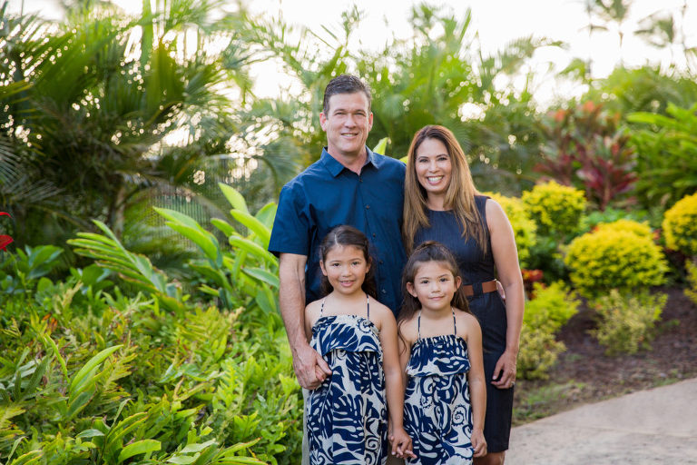 family smiling with tropical foliage in the background