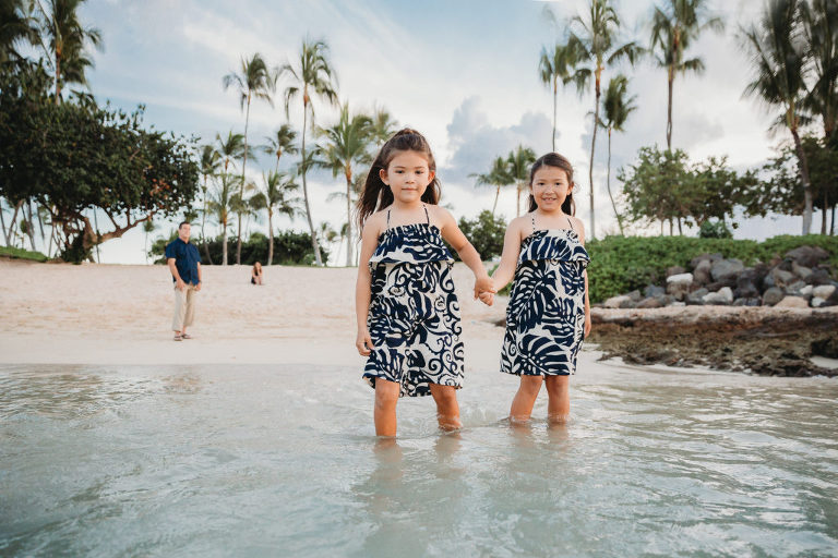 two sisters holding hands in the water during a family photography shoot